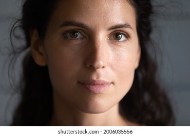 Close Up Portrait Of Serious Beautiful Millennial Young Woman With Smooth Healthy Skin And Black Hair Looking At Camera. Face Of Hispanic 30s Female Model On Grey Background. Beauty Care Concept