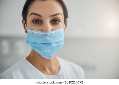 Close Up Portrait Of A Serious Dark-haired Mature Caucasian Female Dermatologist Wearing A Disposable Face Mask