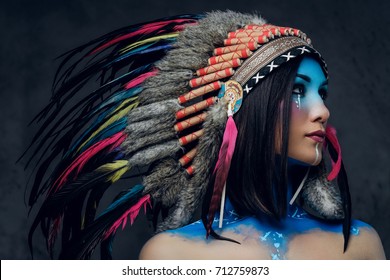 Close Up Portrait Of Shamanic Female With Indian Feather Hat And Colorful Makeup.