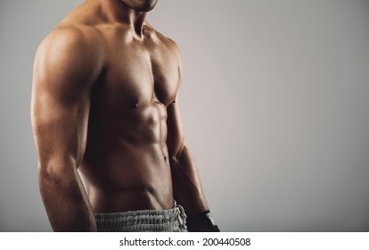 Close up portrait of shirtless young man standing on grey background. Man with muscular body. Health and fitness concept with copyspace for your text. - Powered by Shutterstock