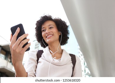 Close up portrait of smiling african american woman listening to music with headphones and mobile phone