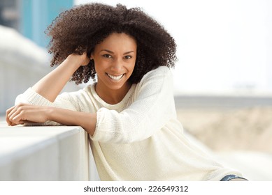 Close Up Portrait Of A Smiling African American Woman With Curly Hair Sitting Outdoors