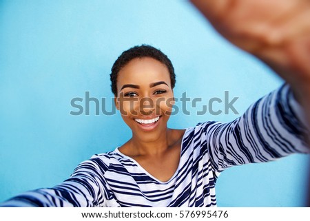 Close up portrait of smiling african american woman taking selfie against blue wall
