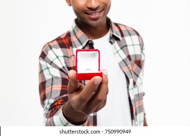 Close up portrait of a smiling african man holding open box with a wedding ring isolated over white background