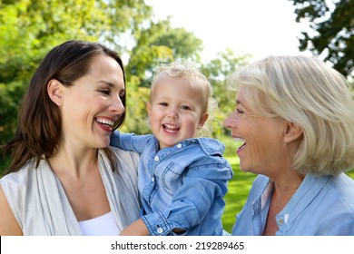 Close Up Portrait Of A Smiling Baby With Mother And Grandmother