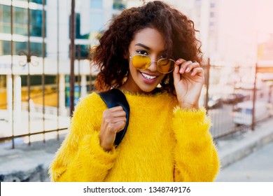 Close  Up Portrait  Of  Smiling Black Woman In The Stylist Yellow Sweater And Sunglasses Enjoying Sunny Day. College Girl Walking Over The City.