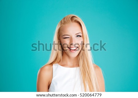 Close up portrait of a smiling blonde woman winking and looking at camera isolated on the blue background