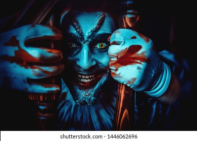 A close up portrait of a smiling clown from a horror film behind the railings. Halloween, carnival. - Shutterstock ID 1446062696