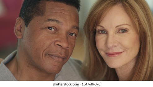 Close Up Portrait Of Smiling Mixed Race Senior Couple Looking At Camera. Happy Older African American Husband And Caucasian Wife At Home