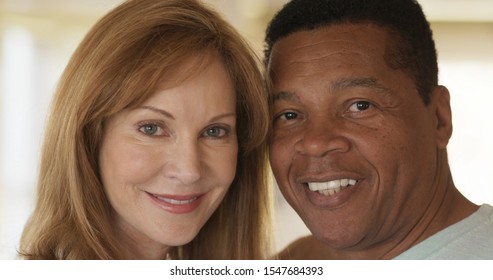 Close Up Portrait Of Smiling Mixed Race Senior Couple Looking At Camera. Happy Older African American Husband And Caucasian Wife At Home