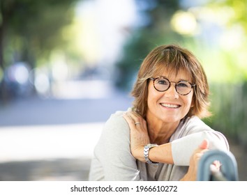 Close Up Portrait Smiling Older Woman Sitting On Park Bench Outside 