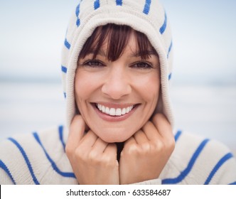 Close up portrait of smiling woman wearing hooded sweater at beach during winter - Powered by Shutterstock