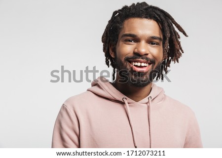 Close up portrait of a smiling young african man wearing hoodie standing isolated over white background, looking at camera