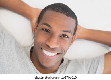 Close up portrait of a smiling young Afro man resting in bed at home