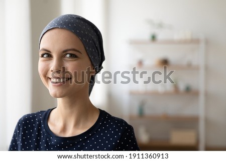 Close up portrait of smiling young Caucasian woman struggle with oncology wear scarf on bald hairless head. Happy millennial female cancer patient feel optimistic, hope for recovery or remission.