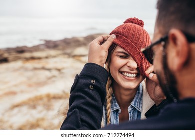 Close up portrait of smiling young couple having fun outdoors. Man and woman enjoying themselves on a winter day at the beach.
