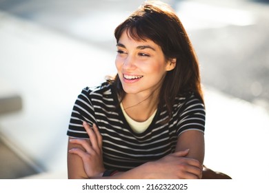 Close Up Portrait Of Smiling Young Female Sitting Outside In The City