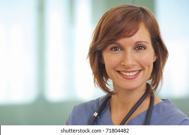 Close Up Portrait Of Smiling Young Woman Doctor In Scrubs