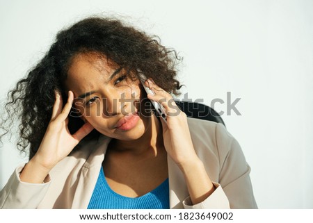 Close up portrait of stressful african curly hairstyle woman talking on the phone. Migraine and headache expression.