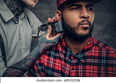 Close Up Portrait Of Tattooed Male Barber Cuts, Beard To A Black Male.