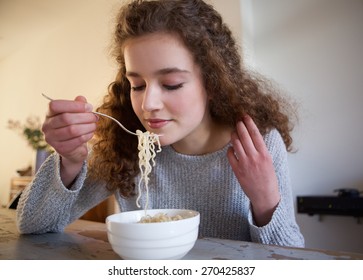 Close Up Portrait Of A Teenage Girl Eating Noodles At Home