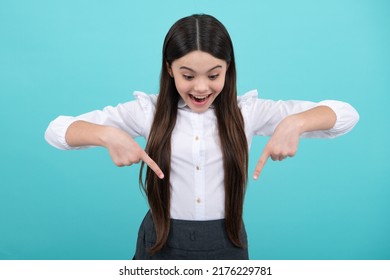 Close Up Portrait Of Teenager Child Girl Showing At Copy Space, Pointing Down To Ads Advertising, Isolated Over Yellow Background. Mock Up Copy Space. Excited Face.