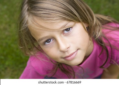 Close up portrait of a ten year old girl, smiling up at the camera. Positive emotion