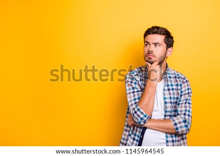 Close up portrait of thoughtful man who looks away touching his chin and weighs the pluses and minuses of the offer isolated on bright yellow background with copy space for text