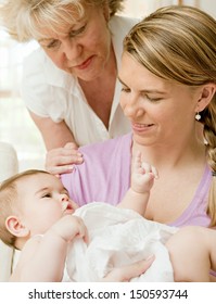 Close Up Portrait Of Three Generations Of Women Being Close, Grandmother, Mother And Baby Daughter At Home, Being Calm And Relaxing Together Around Each Other.