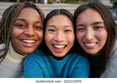 Close Up Portrait Of Three Multicultural Female Friends Looking At Camera Smiling. Faces Of Young Women Together Hugging, Outdoors Inspiring Happiness And Comfort. Concept Of Equality. Empowered Women