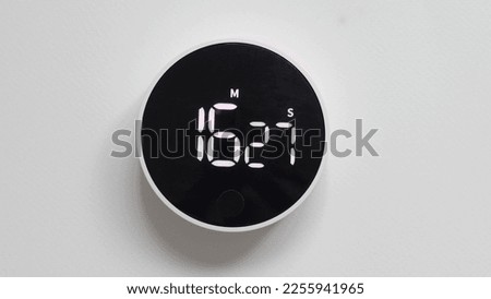close portrait timer lies on white table deadline time expiration concept. round timer lies isolated on white background timer with black screen and white LED backlight counts down the time.