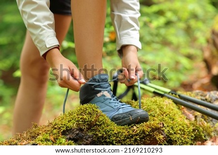 Close up portrait of a trekker tying shoelaces of boots in a forest
