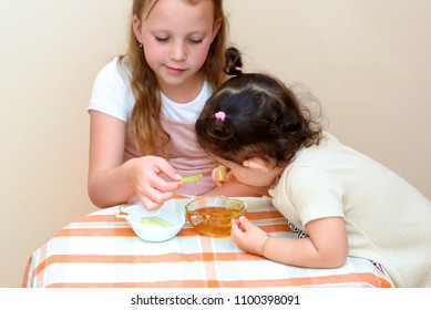 Close Up Portrait Of  Two Funny Cute Little Girl Eat Apple With Honey Indoor. Jewish Children Dipping Apple Slices Into Honey On Rosh HaShanah The Jewish New Year.Happy Family Celebrate Rosh HaShana. 