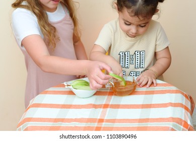 Close Up Portrait Of  Two Funny Cute Little Girl Eat Apple With Honey Indoor. Jewish Children Dipping Apple Slices Into Honey On Rosh HaShanah The Jewish New Year.Happy Family Celebrate Rosh HaShana. 