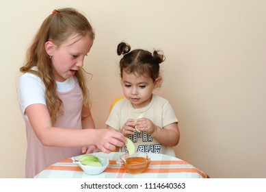 Close Up Portrait Of  Two Funny Cute Little Girl Eat Apple With Honey Indoor. Jewish Children Dipping Apple Slices Into Honey On Rosh HaShanah The Jewish New Year.Happy Family Celebrate Rosh HaShana. 