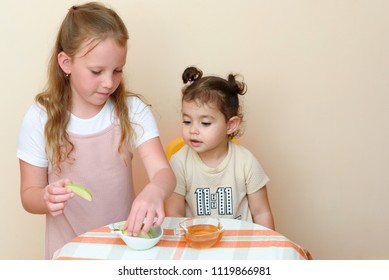 Close up portrait of  two funny cute little girl eat apple with honey indoor. Jewish children dipping apple slices into honey on Rosh HaShanah the Jewish New Year.Happy family celebrate Rosh HaShana. 