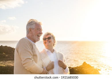 close up and portrait of two happy and active seniors or pensioners having fun and enjoying looking at the sunset smiling with the sea - old people outdoors enjoying vacations together - Shutterstock ID 1921685030