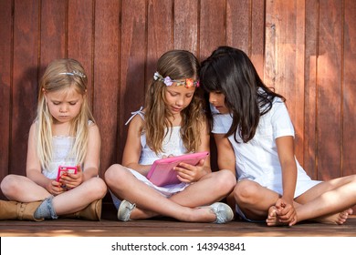 Close Up Portrait Of Two Kids With Tablet And Smart Phone Outdoors.