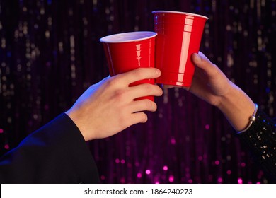 Close up portrait of unrecognizablcouple clinking redplastic cups while drinking alcohol at party, copy space - Powered by Shutterstock