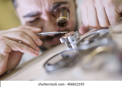 Close up portrait of a watchmaker at work. He is wearing specialist magnifying glass.