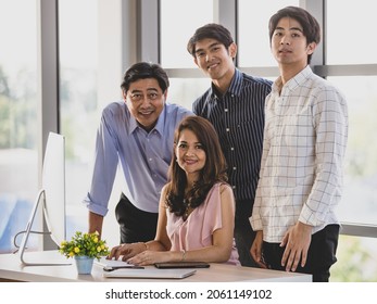Close Up And Portrait Wealthy Successful Asian Business Family Looking At Camera, Smiling Confidently, Proudly And Happy While Sitting, Working And Using Computer In Comfortable Office During The Day