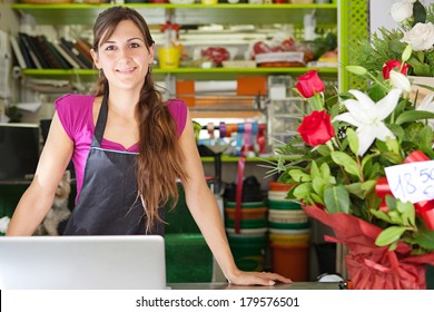 Close up portrait of a welcoming florist business woman owner proudly standing at her flower shop counter using a laptop computer and smiling. Small business technology. - Powered by Shutterstock