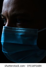 Close Up Portrait Of A White Man Wearing A Face Mask And Looking Worried. Shallow Depth Of Field Isolated On Black Background.