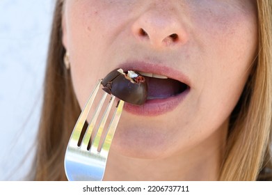 Close Up Portrait Of Woman Biting A Chocolate Candy On Light Backround. Happy 35 Years Old Woman Eating Chocolate.