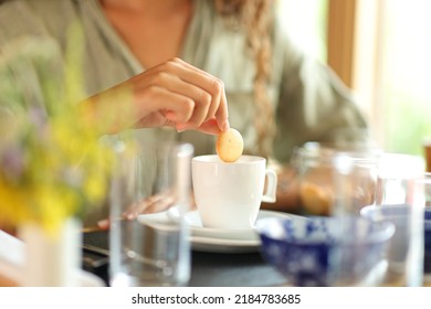 Close up portrait of a woman hand dipping cookie in milk in a restaurant - Powered by Shutterstock