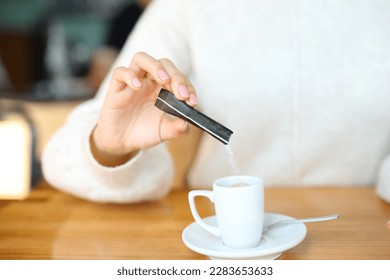 Close up portrait of a woman hand throwing suggar in a coffee cup in a bar - Powered by Shutterstock