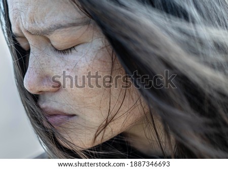 A close up portrait of a woman with her eyes closed in deep depression and sadness, staning in the cold winter day.