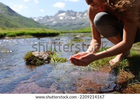 Close up portrait of a yogi cupping hands catching water from river in the mountain