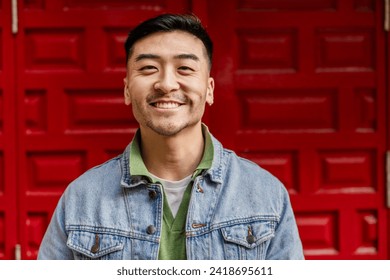 close up portrait of young adult of asian ethnicity looking at camera smiling on colorful red background - Powered by Shutterstock