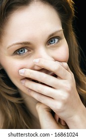 Close Up Portrait Of Young Adult Caucasian Female Laughing With Hand Over Mouth.